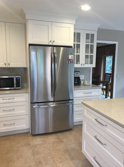 This is an example of a mid-sized transitional u-shaped eat-in kitchen in Detroit with an undermount sink, recessed-panel cabinets, white cabinets, quartz benchtops, beige splashback, ceramic splashback, stainless steel appliances, ceramic floors, a peninsula, beige floor and beige benchtop.