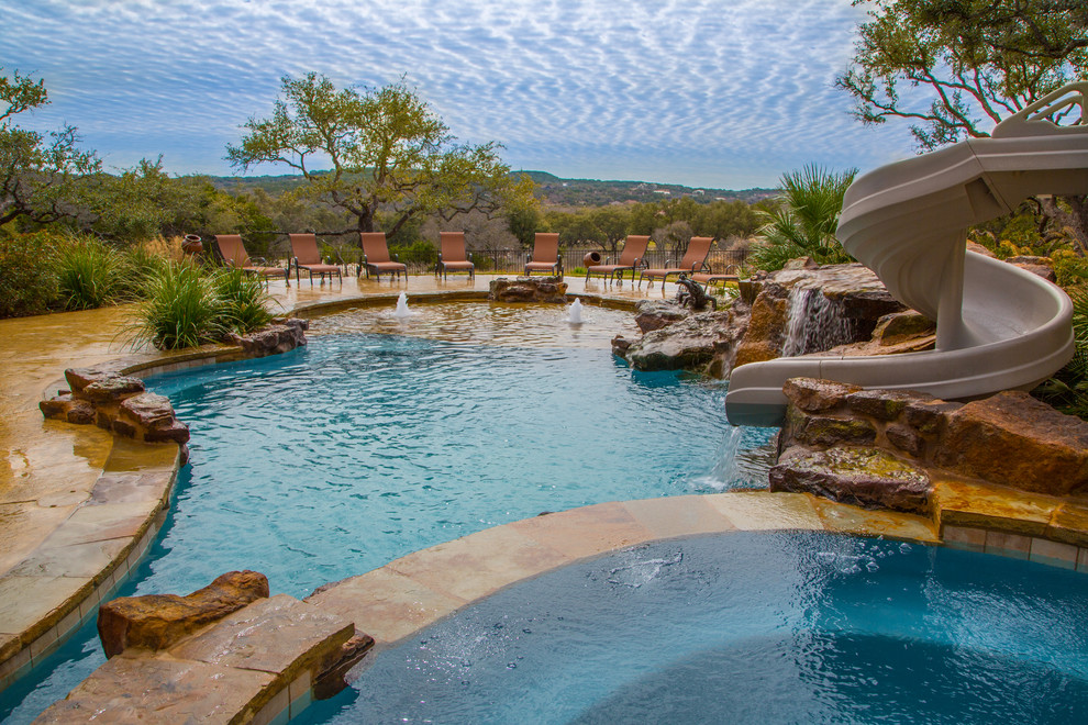 Design ideas for a tropical natural pool in Austin with a water slide.