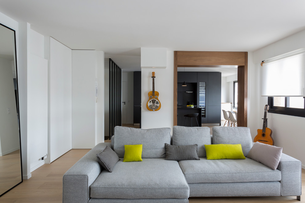 This is an example of an expansive contemporary formal open concept living room in Paris with white walls, light hardwood floors, no fireplace and a wall-mounted tv.