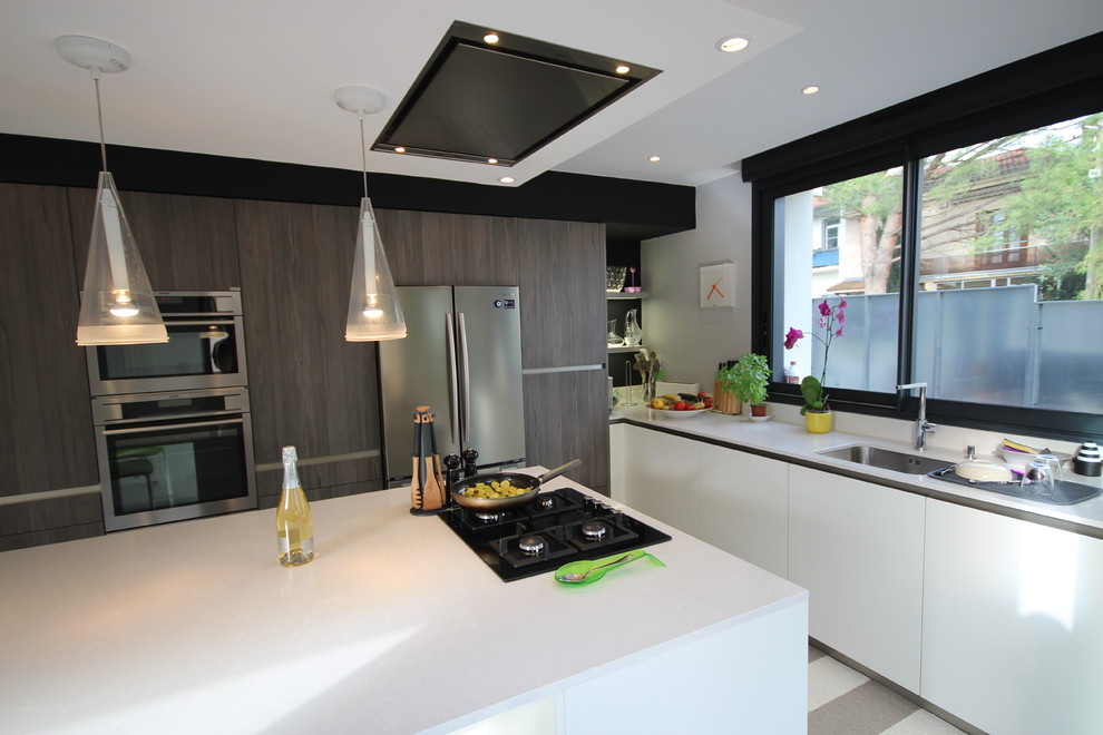 This is an example of a large contemporary u-shaped separate kitchen in Toulouse with a single-bowl sink, beaded inset cabinets, white cabinets, solid surface benchtops, white splashback, stainless steel appliances, carpet, with island and multi-coloured floor.