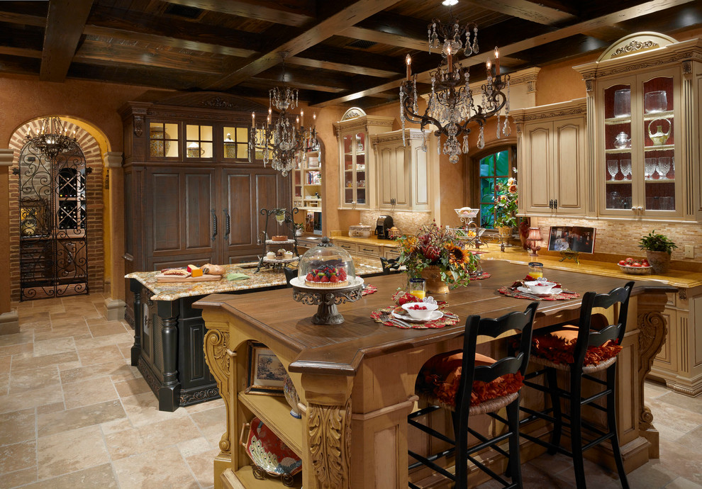 Inspiration for a large mediterranean l-shaped separate kitchen in Orlando with beige cabinets, granite benchtops, beige splashback, panelled appliances, travertine floors, multiple islands, glass-front cabinets, travertine splashback, beige floor and a farmhouse sink.