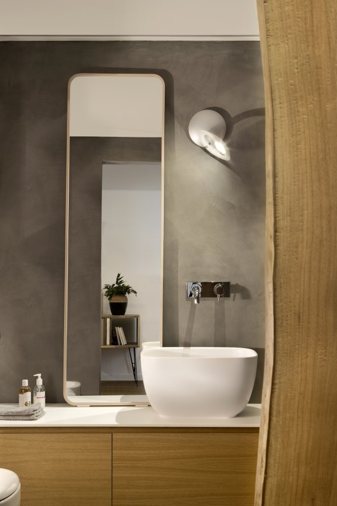 Inspiration for a contemporary master bathroom in Turin with flat-panel cabinets, light wood cabinets, gray tile, grey walls, concrete floors, a vessel sink, solid surface benchtops and grey floor.
