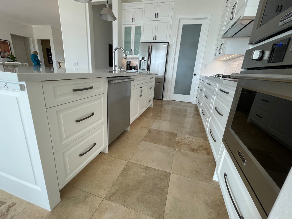 Mid-sized transitional l-shaped open plan kitchen in Phoenix with a single-bowl sink, raised-panel cabinets, quartz benchtops, stainless steel appliances, porcelain floors, with island, beige floor and white benchtop.