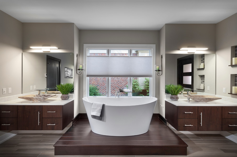 Inspiration for a mid-sized modern master bathroom in Detroit with flat-panel cabinets, dark wood cabinets, a freestanding tub, a corner shower, a one-piece toilet, white tile, subway tile, beige walls, ceramic floors, a vessel sink and engineered quartz benchtops.