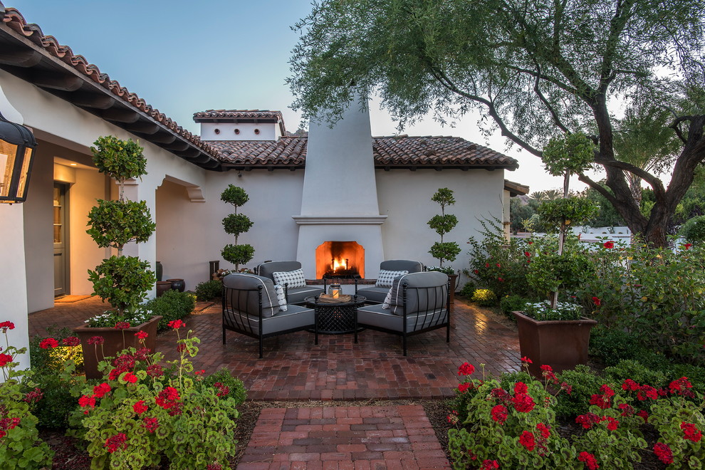 Design ideas for a contemporary front yard patio in Phoenix with with fireplace and brick pavers.