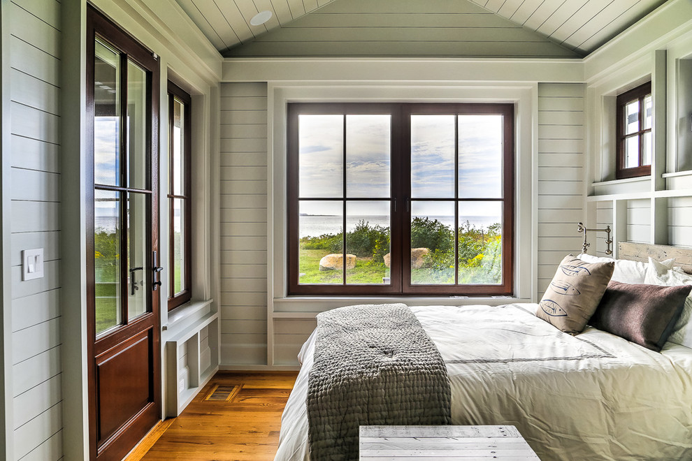 Design ideas for a large beach style guest bedroom in Boston with white walls and medium hardwood floors.