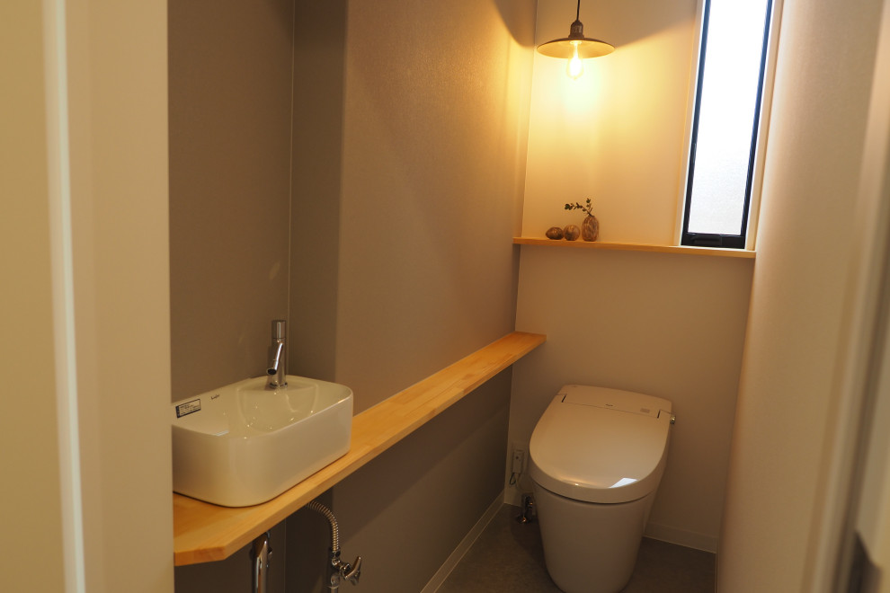Aménagement d'un WC et toilettes moderne avec WC à poser, un mur gris et meuble-lavabo encastré.