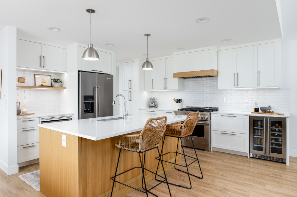 Inspiration for a mid-sized transitional l-shaped light wood floor and beige floor eat-in kitchen remodel in Vancouver with an undermount sink, shaker cabinets, white cabinets, quartzite countertops, white backsplash, subway tile backsplash, stainless steel appliances, an island and white countertops