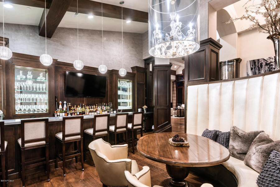 Photo of a large transitional u-shaped seated home bar in Salt Lake City with an undermount sink, recessed-panel cabinets, dark wood cabinets, zinc benchtops, brown splashback, timber splashback, dark hardwood floors, brown floor and grey benchtop.