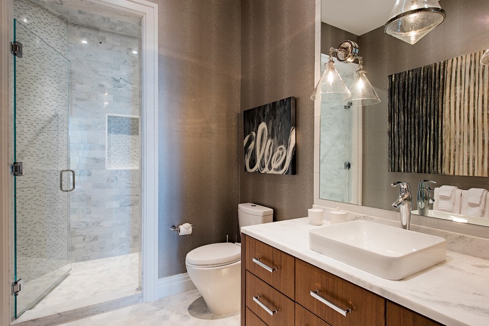 This is an example of a contemporary 3/4 bathroom in Other with flat-panel cabinets, medium wood cabinets, an alcove shower, a two-piece toilet, gray tile, white tile, brown walls, a vessel sink, grey floor, a hinged shower door and white benchtops.