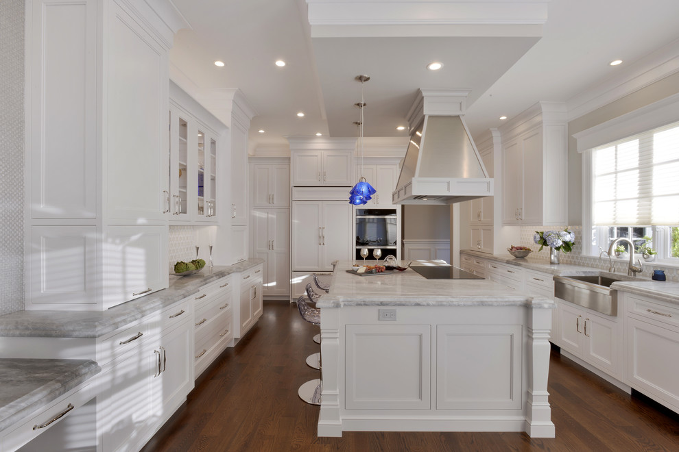 Inspiration for an expansive traditional u-shaped eat-in kitchen in New York with a farmhouse sink, recessed-panel cabinets, white cabinets, marble benchtops, multi-coloured splashback, glass tile splashback, panelled appliances, dark hardwood floors and with island.