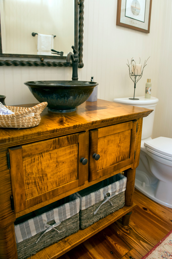 Small transitional powder room in Charleston with furniture-like cabinets, medium wood cabinets, a one-piece toilet, beige walls, medium hardwood floors, a vessel sink and wood benchtops.
