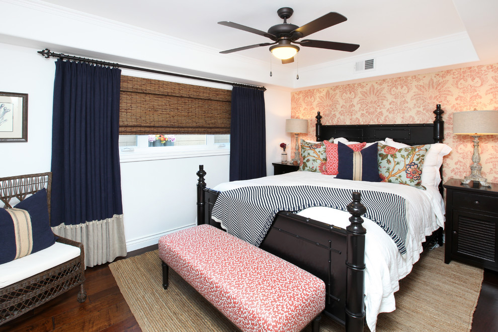 This is an example of a tropical bedroom in Orange County with white walls, dark hardwood floors and no fireplace.