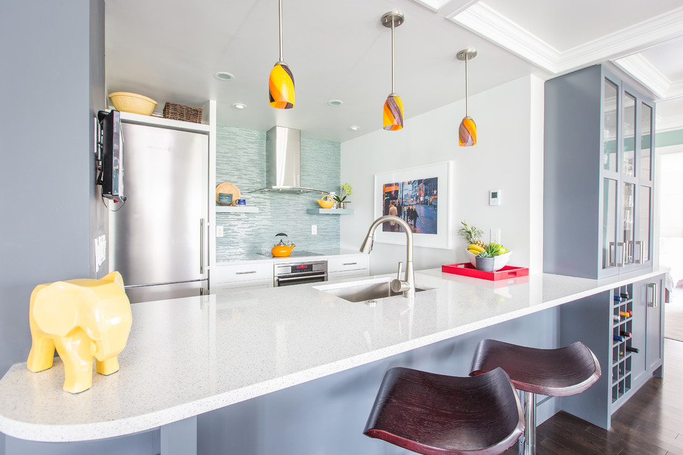 Small eclectic galley open plan kitchen in Vancouver with a single-bowl sink, shaker cabinets, blue cabinets, quartz benchtops, green splashback, glass tile splashback, stainless steel appliances, porcelain floors and no island.