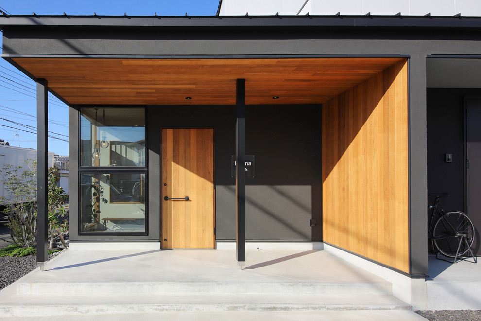 Idée de décoration pour une entrée minimaliste avec un couloir, un mur noir, sol en béton ciré, une porte simple, une porte en bois brun, un sol gris, un plafond en bois et du lambris de bois.