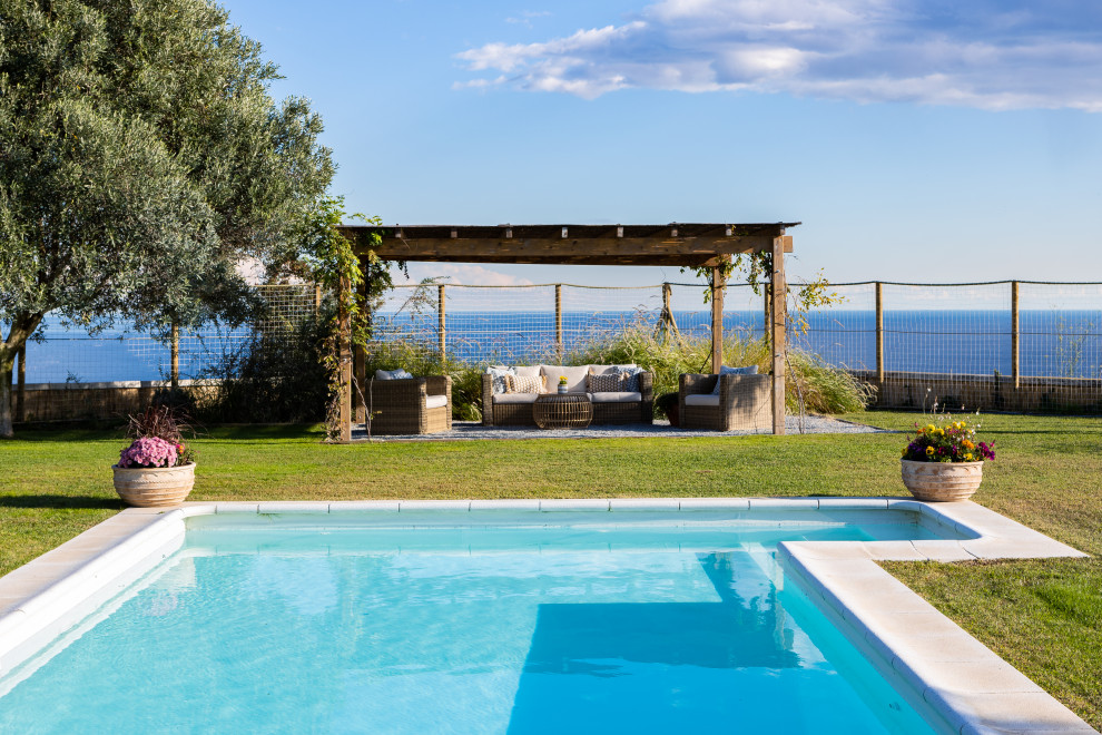 Modelo de piscina alargada mediterránea de tamaño medio en forma de L en patio trasero