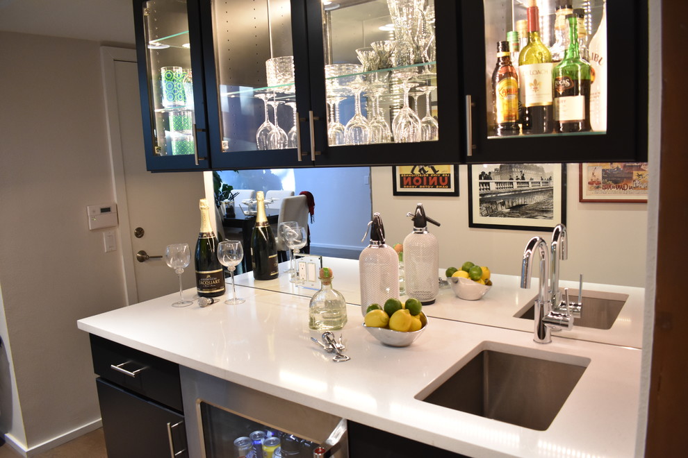 This is an example of a contemporary galley wet bar in Denver with glass-front cabinets, black cabinets, mirror splashback, an undermount sink, medium hardwood floors and brown floor.