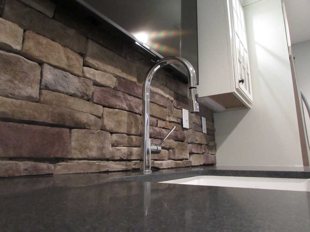 Example of a large walk-out vinyl floor basement design with beige walls, a standard fireplace and a stone fireplace
