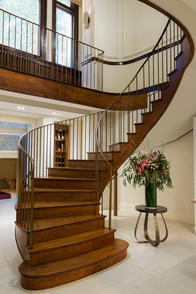 Inspiration for a large eclectic wood curved staircase in London with wood risers and metal railing.
