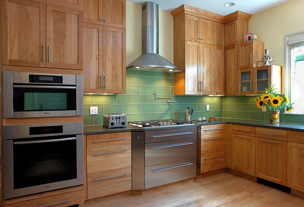 Contemporary kitchen in Boston with glass tile splashback, stainless steel appliances, green splashback, recessed-panel cabinets and medium wood cabinets.