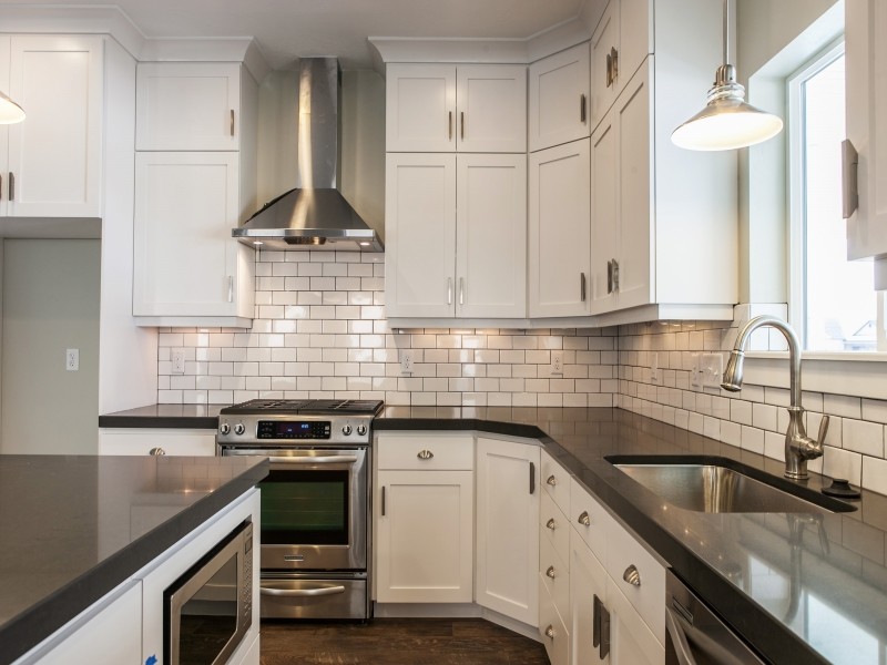 Inspiration for a large arts and crafts l-shaped eat-in kitchen in Salt Lake City with a drop-in sink, recessed-panel cabinets, white cabinets, quartzite benchtops, white splashback, subway tile splashback, stainless steel appliances, medium hardwood floors and with island.