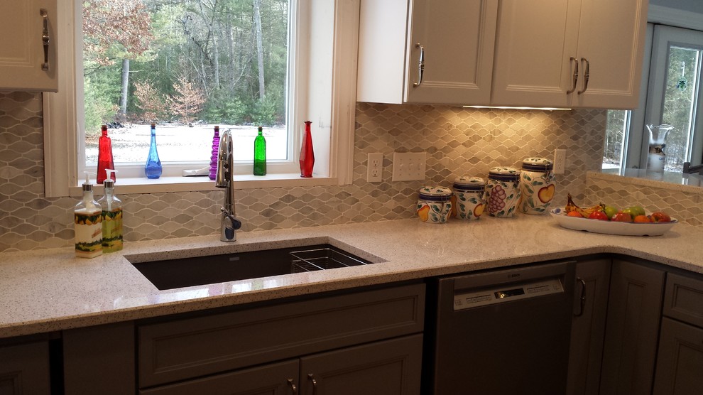 Inspiration for a mid-sized transitional u-shaped kitchen remodel in Boston with a single-bowl sink, gray cabinets, quartz countertops, gray backsplash, mosaic tile backsplash, stainless steel appliances and a peninsula