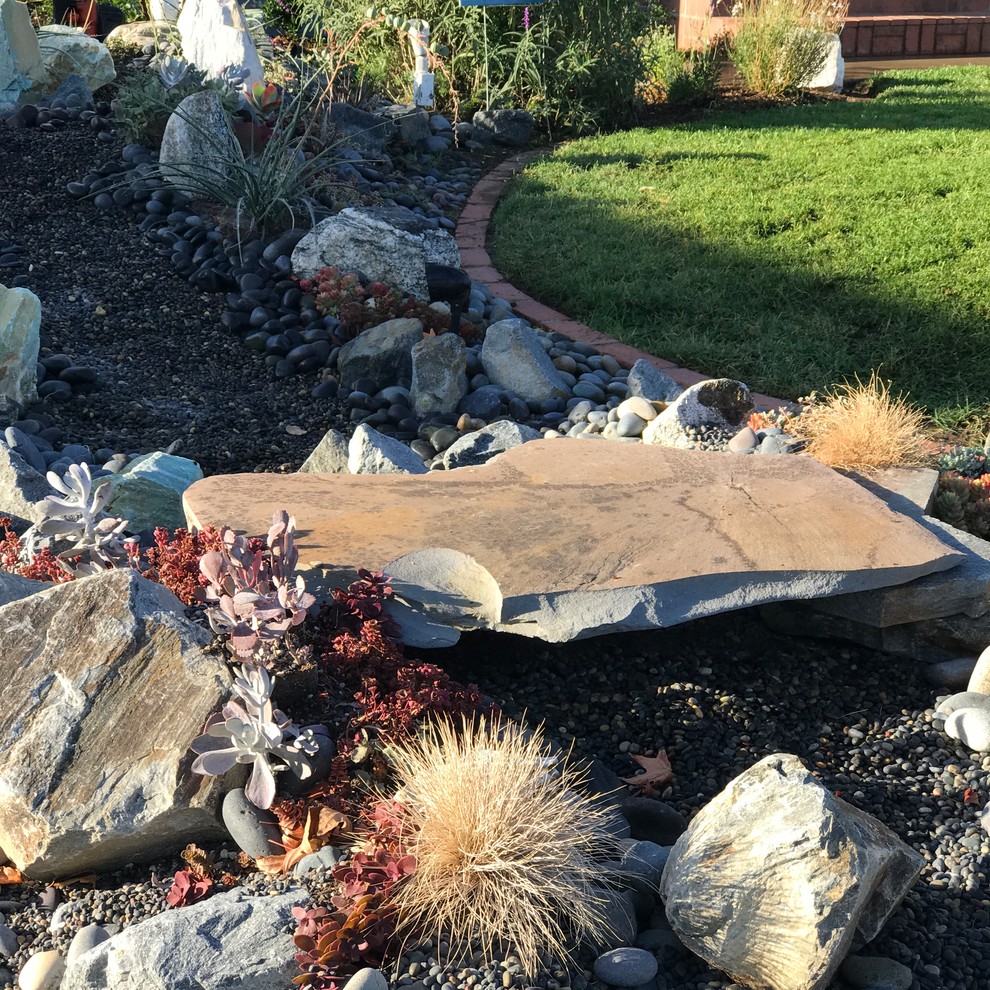 This is an example of a mid-sized transitional courtyard partial sun xeriscape in Orange County with natural stone pavers and a water feature.