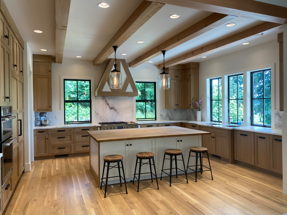 This is an example of a large country u-shaped kitchen pantry in Portland with a double-bowl sink, shaker cabinets, marble benchtops, white splashback, marble splashback, panelled appliances, light hardwood floors, with island, white floor, white benchtop and exposed beam.
