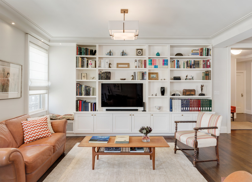 This is an example of a mid-sized transitional enclosed living room in New York with white walls, dark hardwood floors, no fireplace, a built-in media wall, a library and brown floor.
