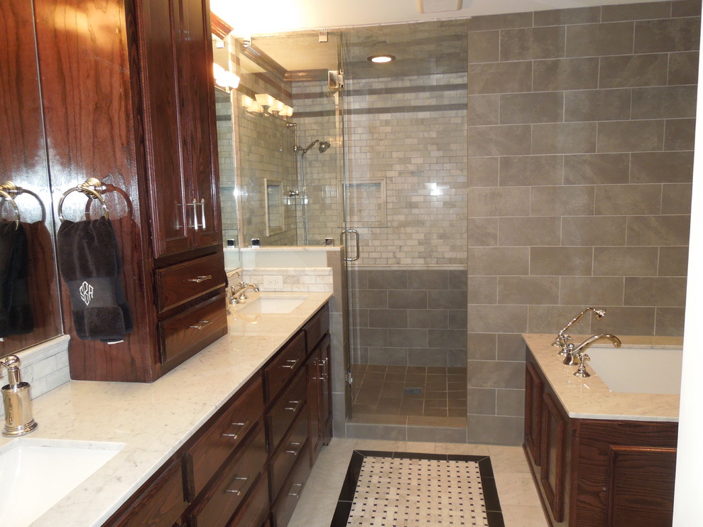 Example of a transitional gray tile and stone tile bathroom design in Dallas with an undermount sink, shaker cabinets, medium tone wood cabinets, marble countertops and an undermount tub