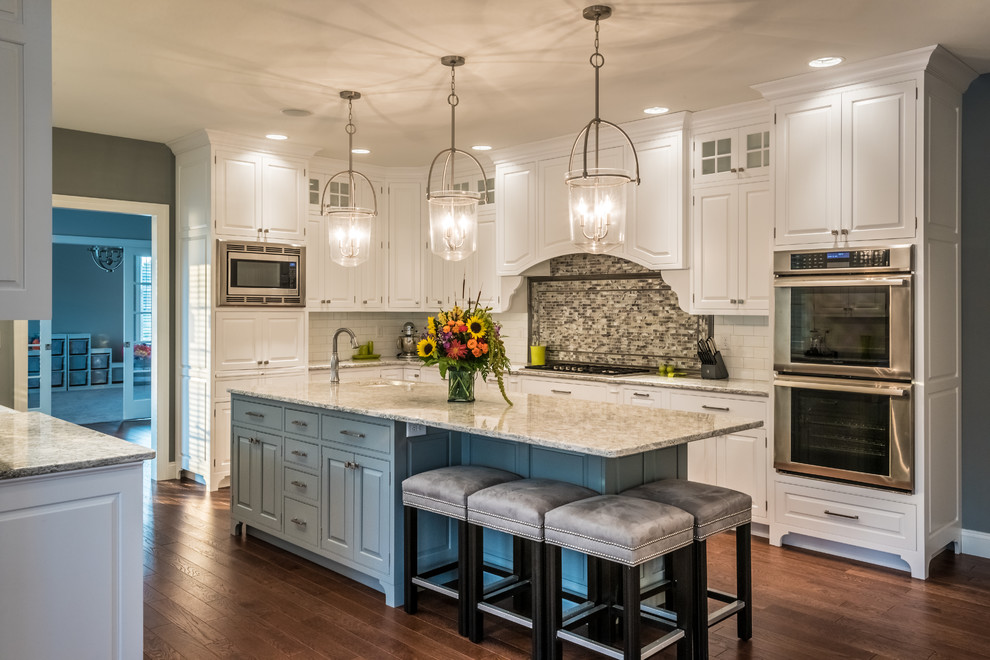 Large transitional galley medium tone wood floor eat-in kitchen photo with beaded inset cabinets, white cabinets, granite countertops, white backsplash, mosaic tile backsplash, stainless steel appliances and an island