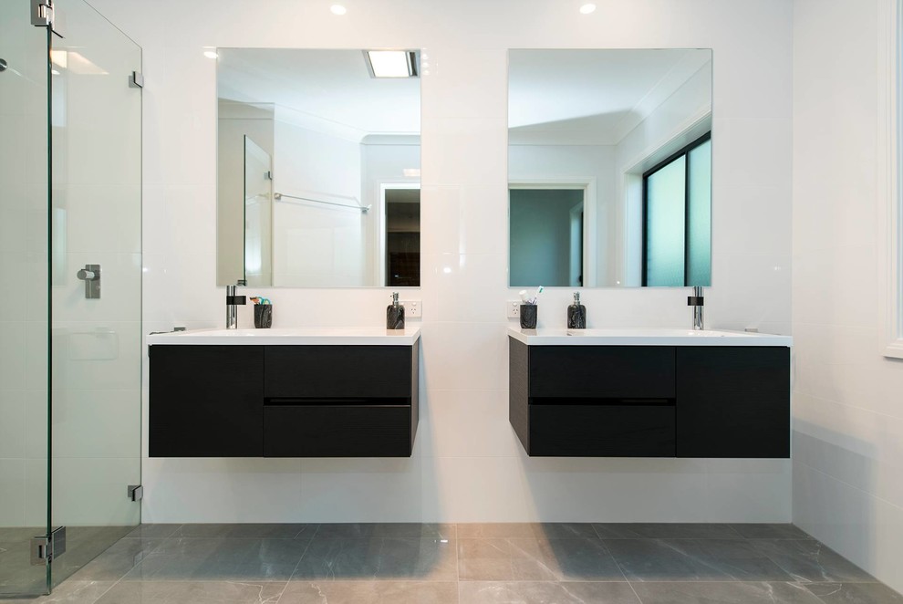 Inspiration for a modern master bathroom in Sydney with flat-panel cabinets, an alcove shower, dark wood cabinets, a wall-mount toilet, white tile, ceramic tile, white walls, porcelain floors, an integrated sink, beige floor, a hinged shower door, white benchtops, a niche, a double vanity and a floating vanity.