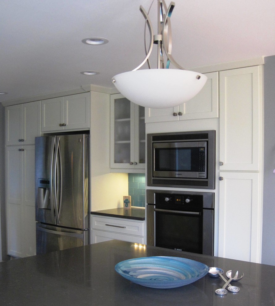 Example of a mid-sized transitional u-shaped dark wood floor home design design in Seattle with an undermount sink, shaker cabinets, white cabinets, quartz countertops, blue backsplash, glass tile backsplash, stainless steel appliances and a peninsula