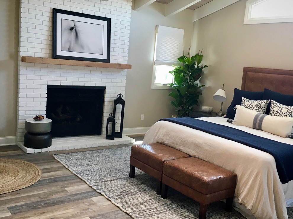 Design ideas for a large beach style guest bedroom in Denver with grey walls, laminate floors, a standard fireplace, a brick fireplace surround and grey floor.