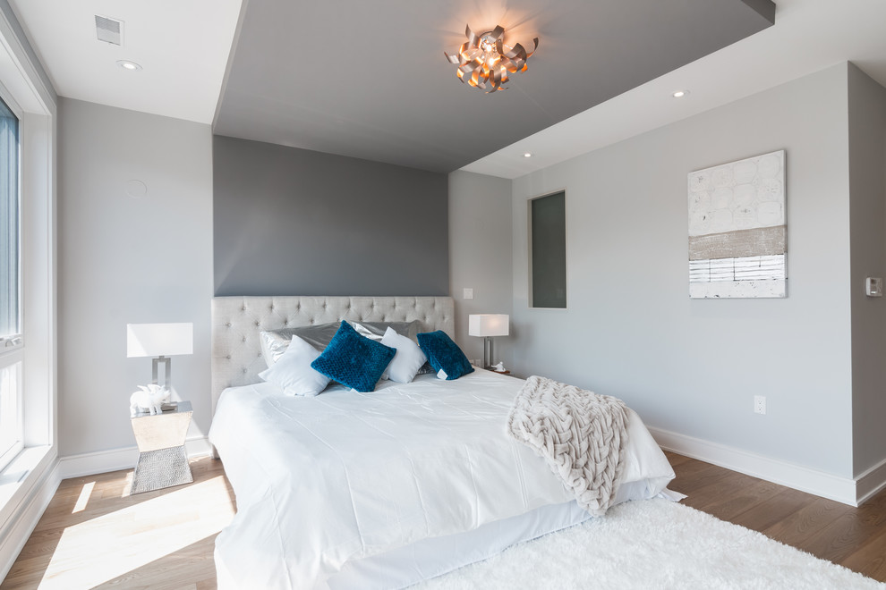 Inspiration for a modern master bedroom in Toronto with grey walls and light hardwood floors.