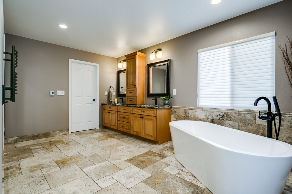 Design ideas for a large traditional master bathroom in Denver with medium wood cabinets, a freestanding tub, a double shower, a one-piece toilet, beige tile, travertine, beige walls, travertine floors, an undermount sink, granite benchtops, recessed-panel cabinets, beige floor and a hinged shower door.