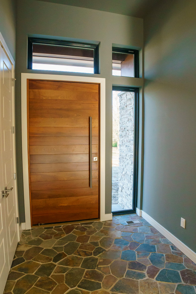 Exemple d'un vestibule tendance de taille moyenne avec un mur gris, un sol en terrazzo, une porte pivot, une porte en bois brun et un sol multicolore.