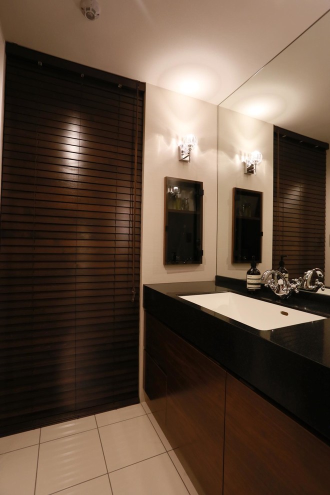 Photo of a modern powder room in Other with flat-panel cabinets, dark wood cabinets, white walls, an integrated sink and white floor.