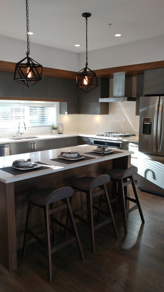 Small modern l-shaped eat-in kitchen in Vancouver with an undermount sink, flat-panel cabinets, grey cabinets, quartz benchtops, white splashback, ceramic splashback, stainless steel appliances, with island, brown floor and white benchtop.