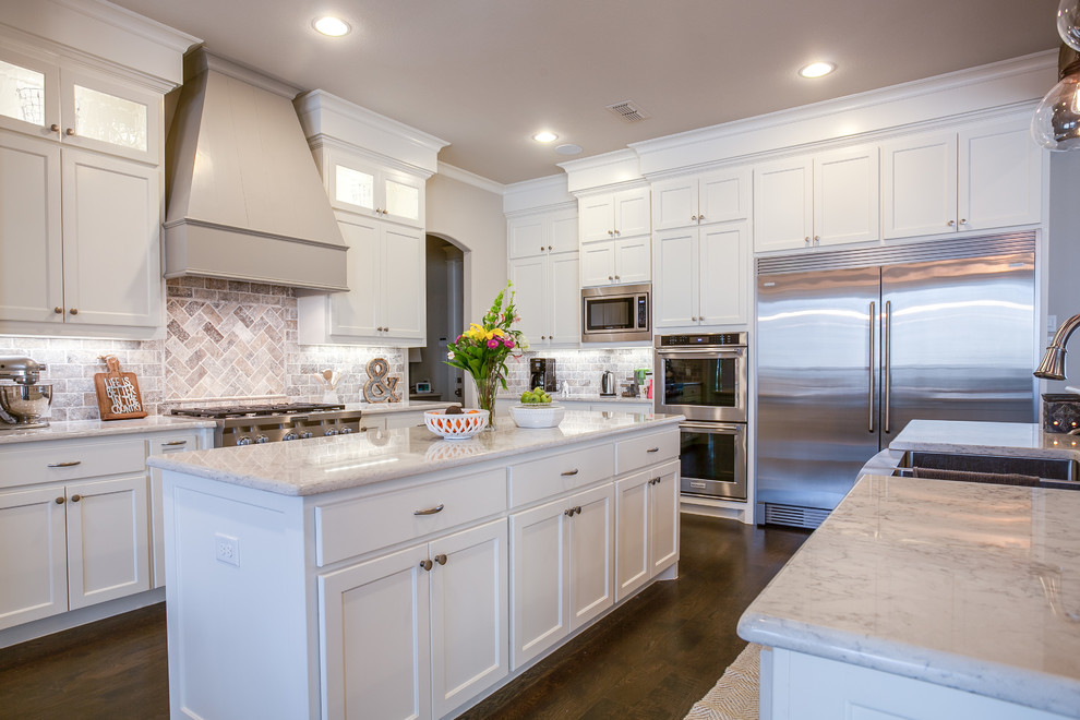Large country u-shaped open plan kitchen in Dallas with shaker cabinets, white cabinets, marble benchtops, grey splashback, stone tile splashback, stainless steel appliances, dark hardwood floors, multiple islands and a farmhouse sink.