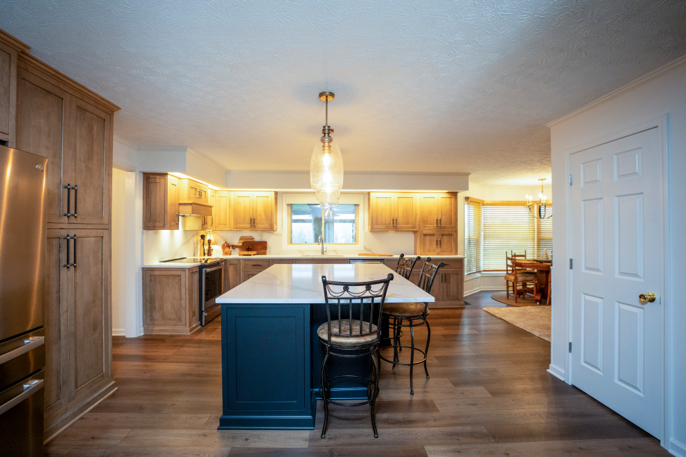 Eat-in kitchen - large transitional l-shaped medium tone wood floor and brown floor eat-in kitchen idea with a single-bowl sink, shaker cabinets, medium tone wood cabinets, quartz countertops, white backsplash, quartz backsplash, stainless steel appliances, an island and white countertops