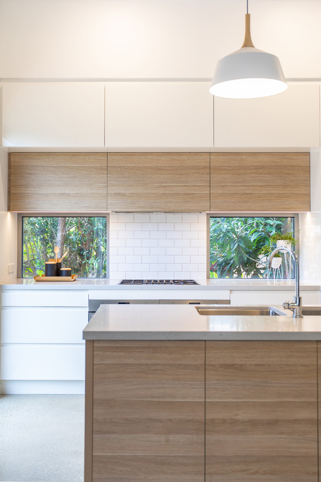 Design ideas for a mid-sized contemporary galley kitchen pantry in Adelaide with an undermount sink, flat-panel cabinets, light wood cabinets, quartz benchtops, white splashback, subway tile splashback, stainless steel appliances, concrete floors, with island, grey floor and grey benchtop.