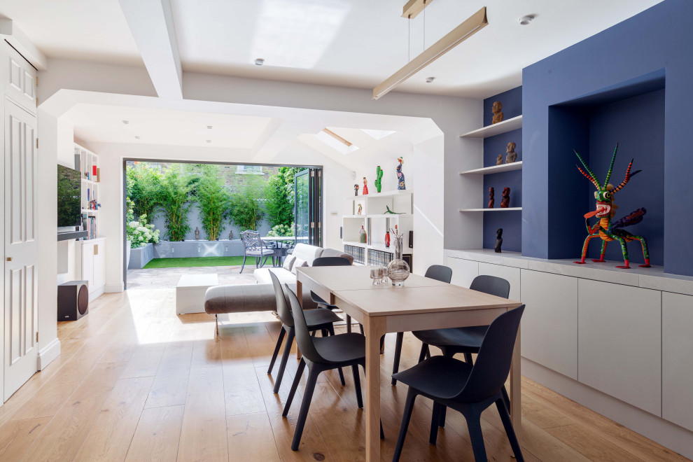 Photo of a large contemporary open plan dining room in London with blue walls, medium hardwood flooring and feature lighting.
