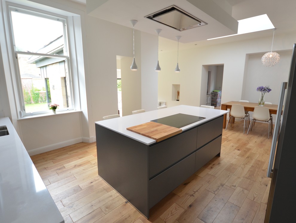 Mid-sized contemporary u-shaped eat-in kitchen in Glasgow with a double-bowl sink, flat-panel cabinets, grey cabinets, limestone benchtops, black splashback, marble splashback, black appliances, dark hardwood floors, with island and brown floor.
