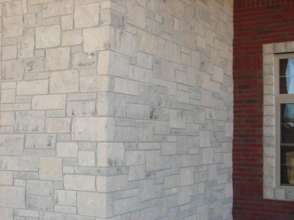 Inspiration for a traditional grey house exterior in Other with stone veneer.