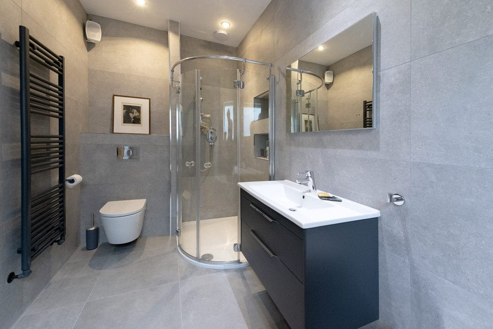 Inspiration for a mid-sized contemporary kids bathroom in Other with a corner shower, a wall-mount toilet, gray tile, porcelain tile, grey walls, porcelain floors, a wall-mount sink, grey floor, a sliding shower screen, a single vanity and a floating vanity.