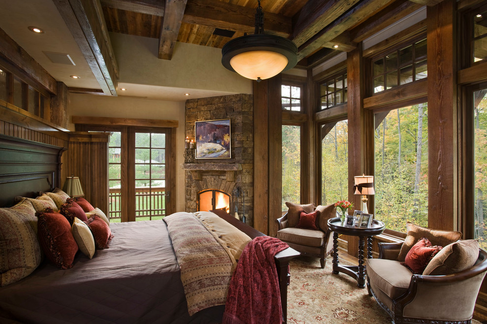 This is an example of a country bedroom in Other with beige walls, a stone fireplace surround and a corner fireplace.