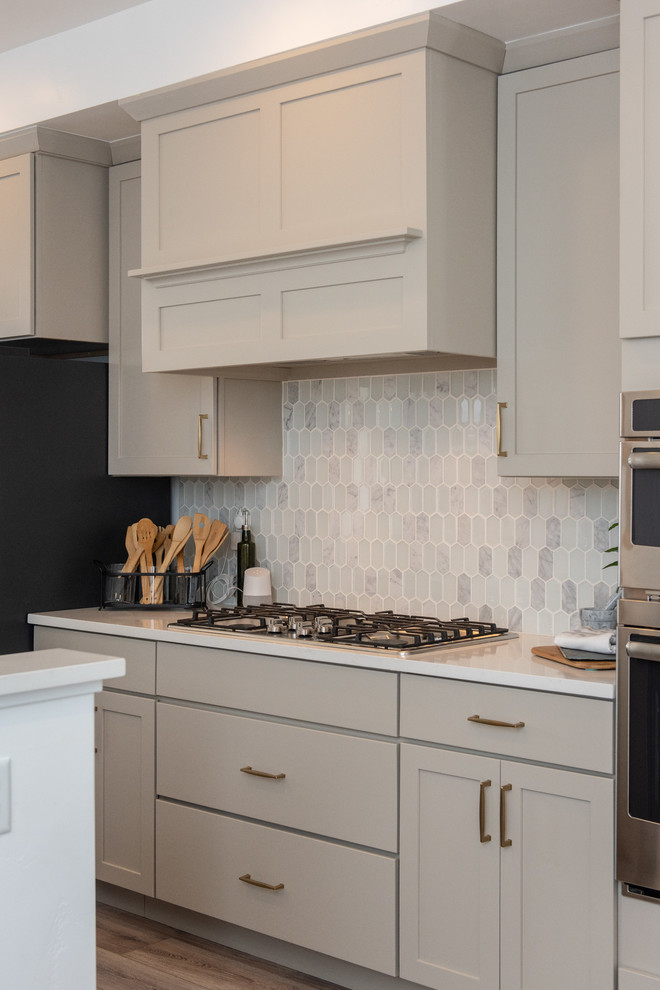 Inspiration for a mid-sized transitional u-shaped eat-in kitchen in Salt Lake City with an undermount sink, recessed-panel cabinets, grey cabinets, quartzite benchtops, white splashback, ceramic splashback, stainless steel appliances, vinyl floors, with island, brown floor and white benchtop.