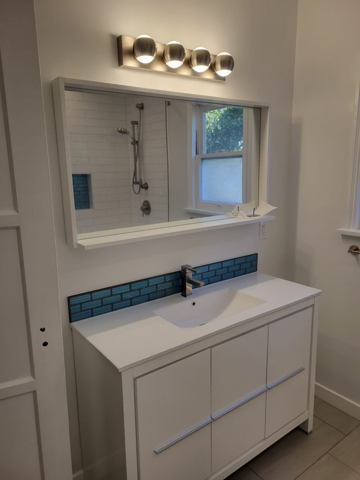 Photo of a medium sized traditional shower room bathroom in Los Angeles with flat-panel cabinets, white cabinets, a corner bath, a shower/bath combination, a one-piece toilet, white tiles, porcelain tiles, white walls, ceramic flooring, an integrated sink, tiled worktops, grey floors, a shower curtain, white worktops, a single sink and a freestanding vanity unit.