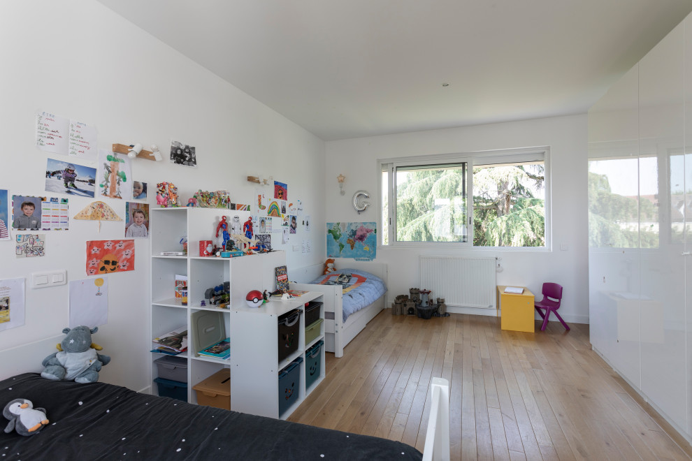 Exempel på ett stort modernt pojkrum kombinerat med sovrum och för 4-10-åringar, med ljust trägolv, brunt golv och vita väggar